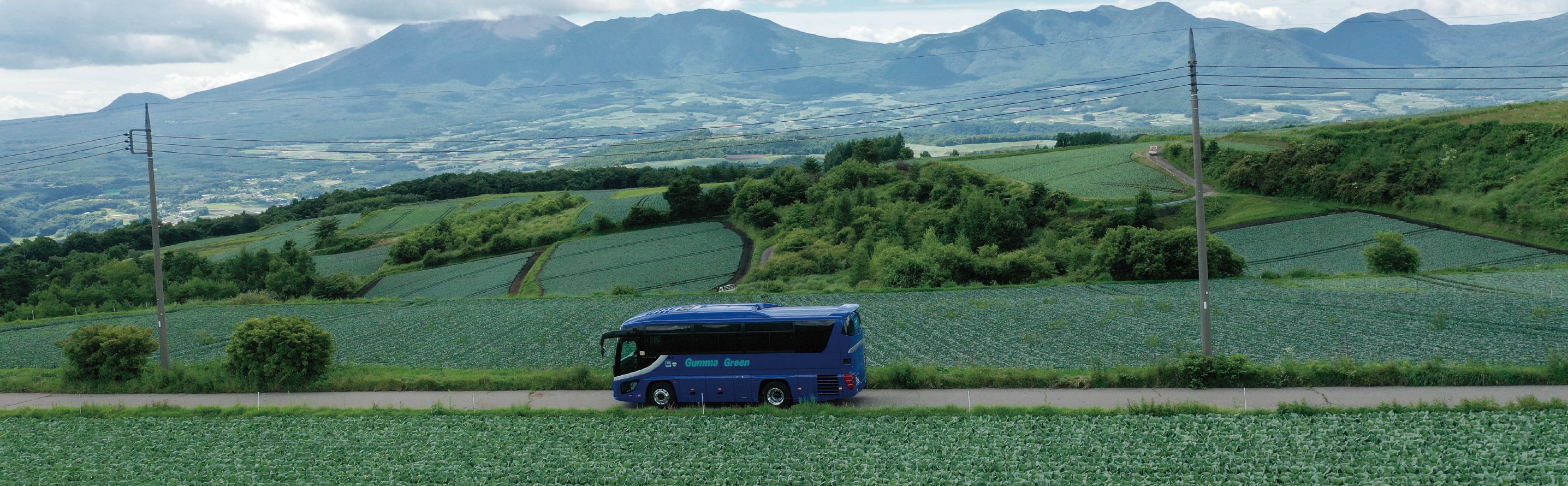 嬬恋村の広大な緑の風景を走るバス